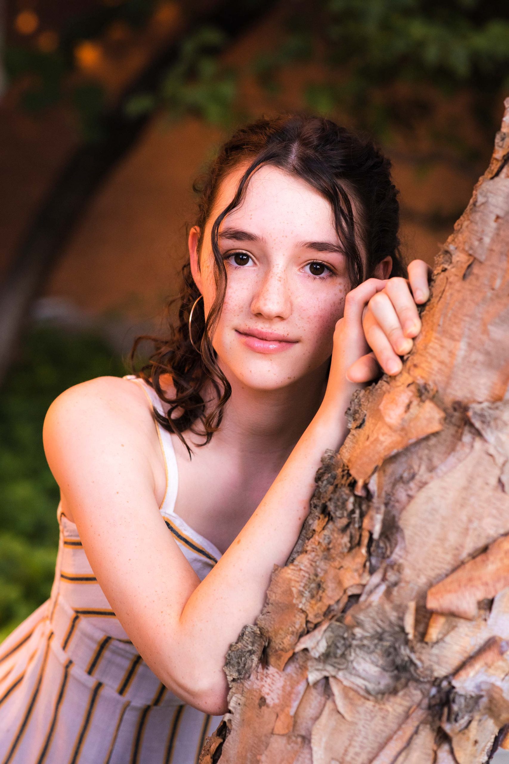 Teen girl leaning on birch tree.