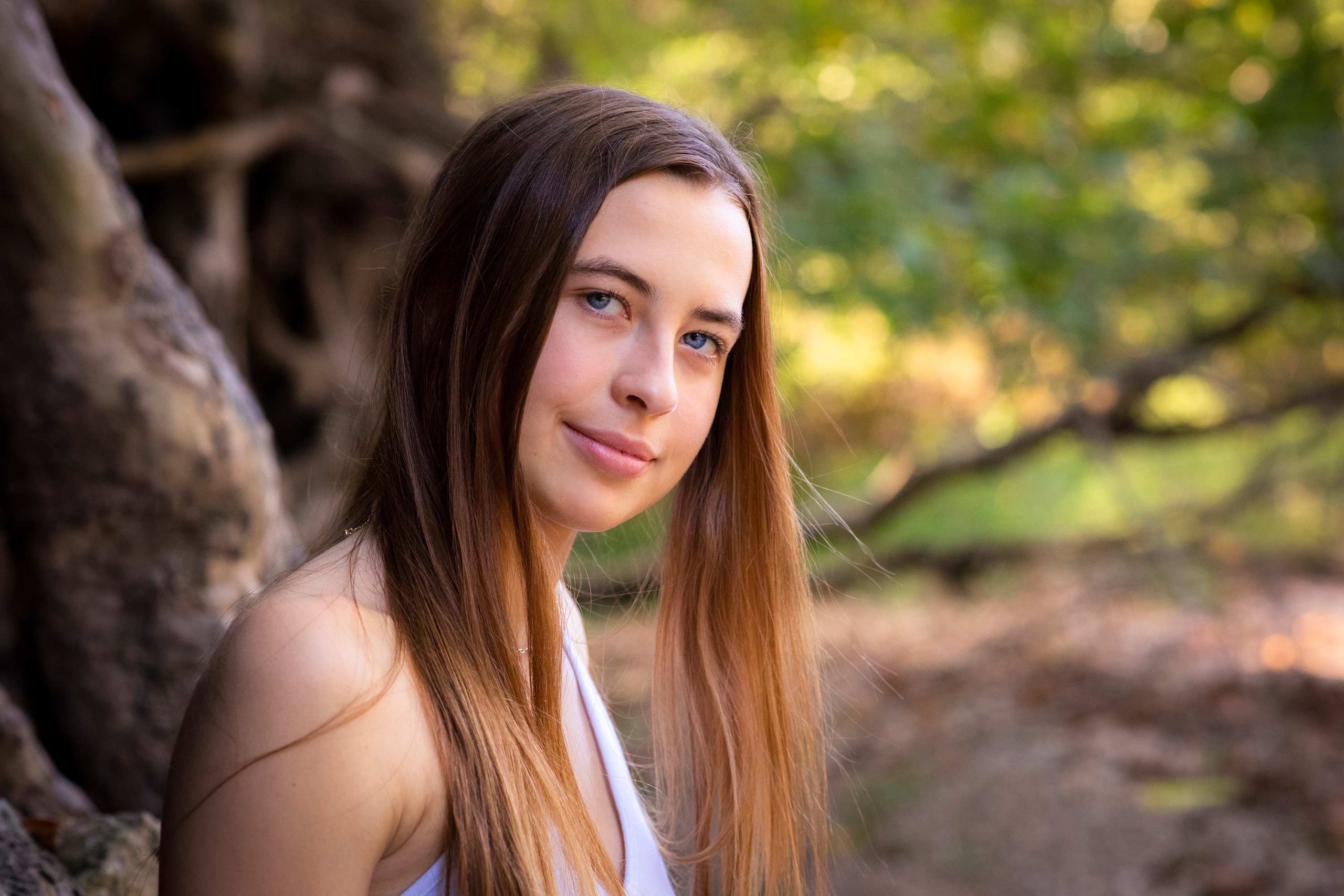 Senior girl leaning against a tree in a creek bed.