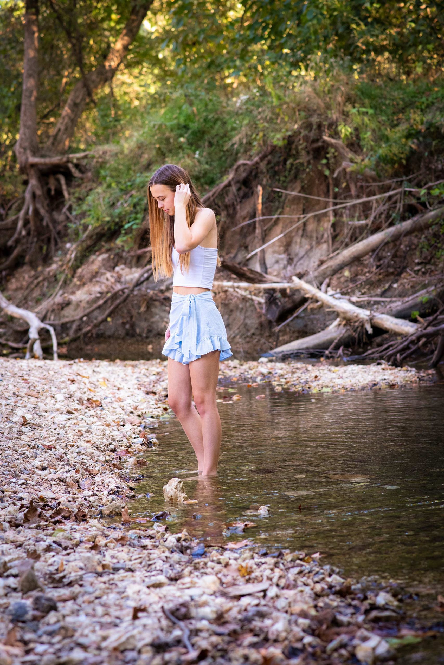 Senior girl standing in the cool waters of a creek in late summer.