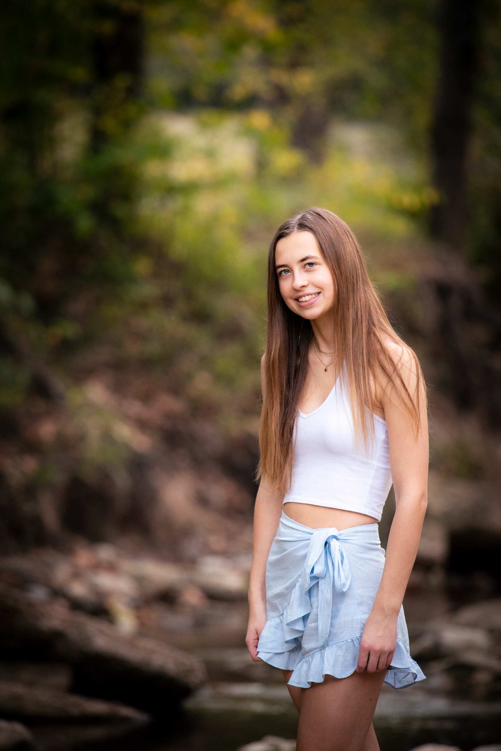 Senior girl standing next to a creek in late summer.