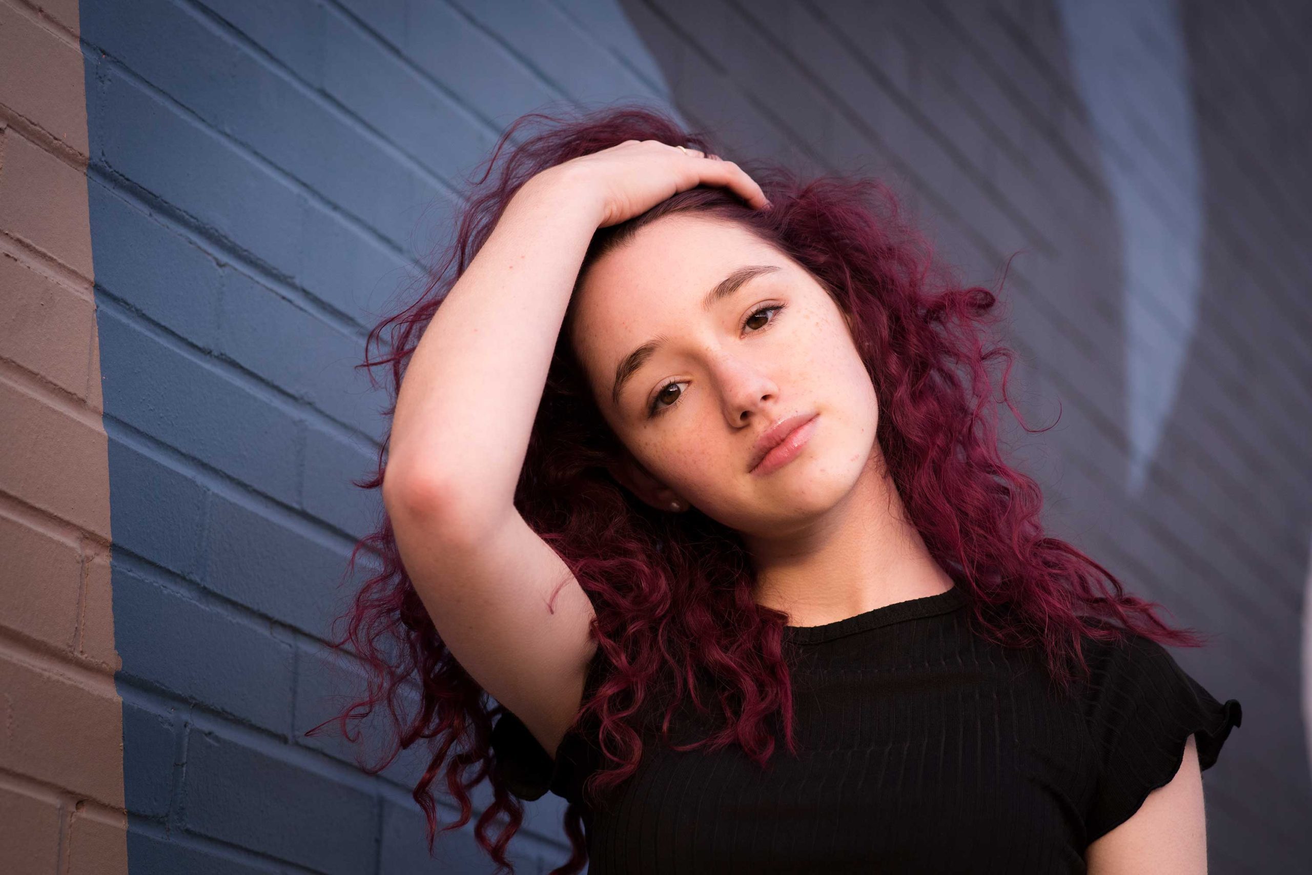 Teen girl with red colored hair against graffiti wall.