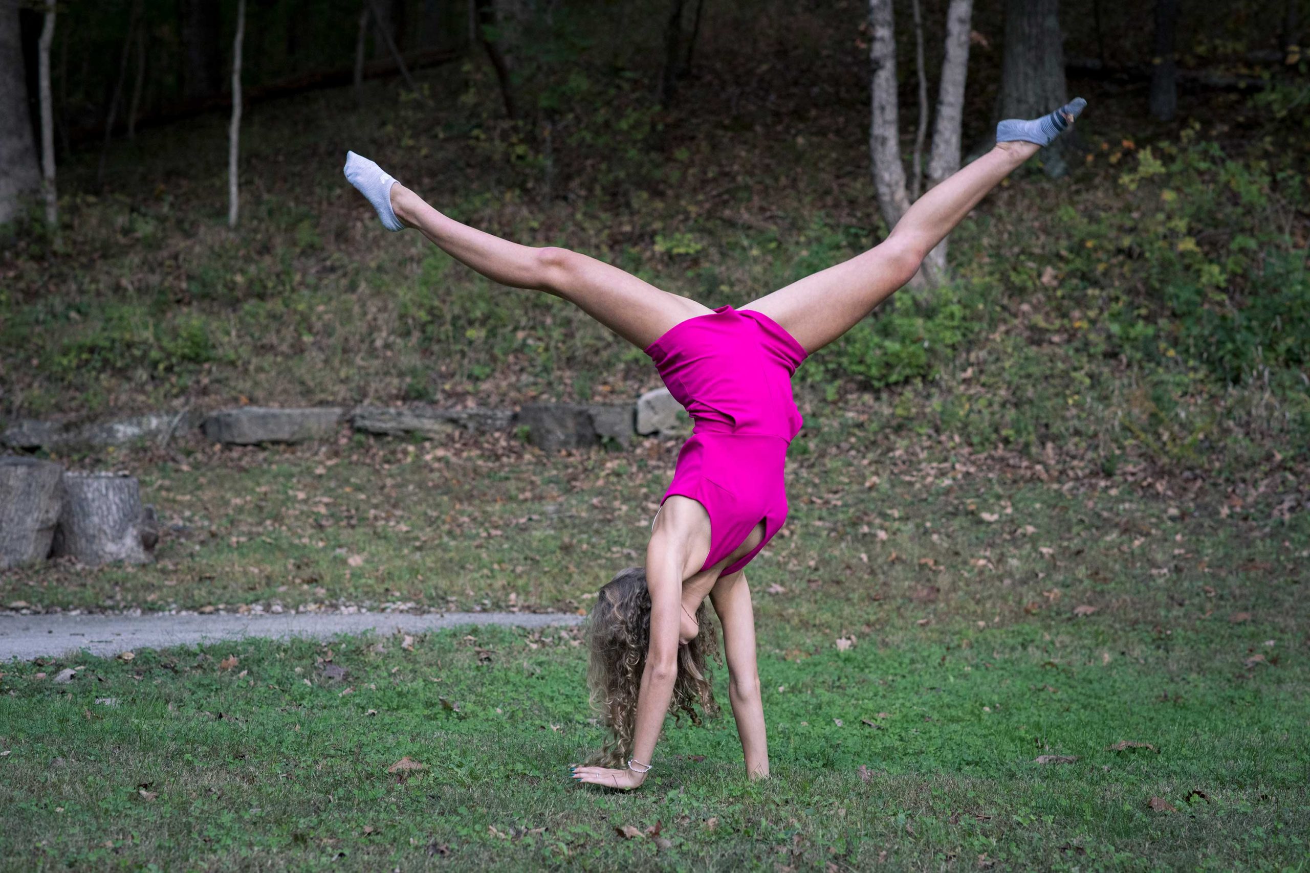 Senior Girl in Woods doing cartwheel during Autumn.