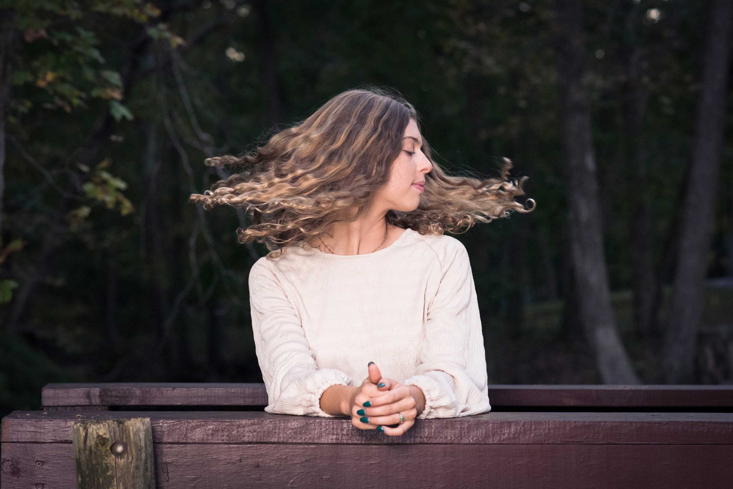 Senior Girl in woods flipping hair during Autumn.