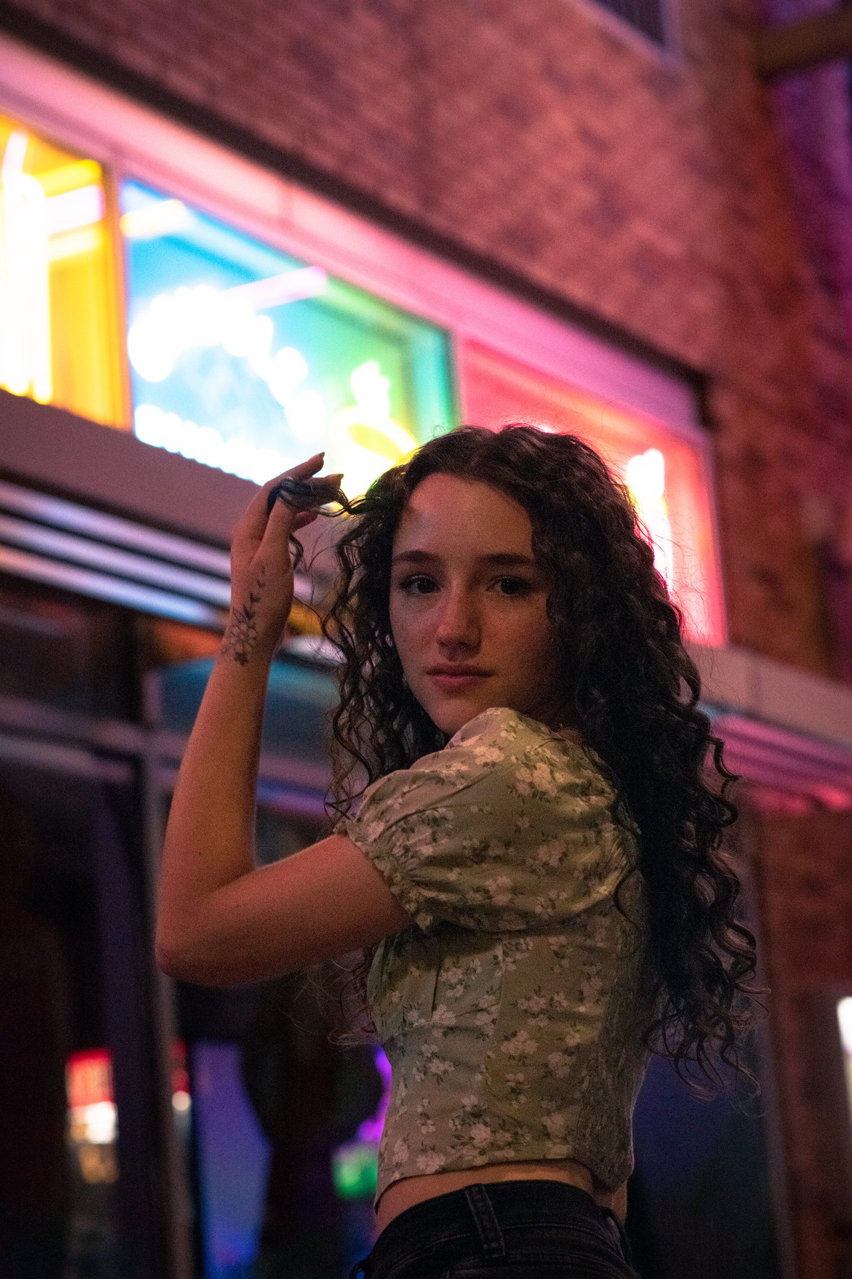 Senior Girl at night in urban setting with neon lights.